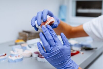 Gloved hands holding a denture.